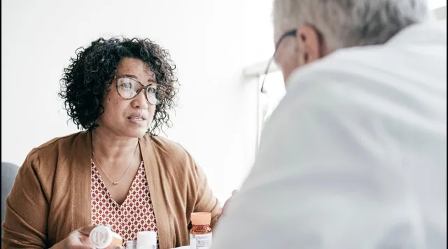 Person holding medication and speaking with physician