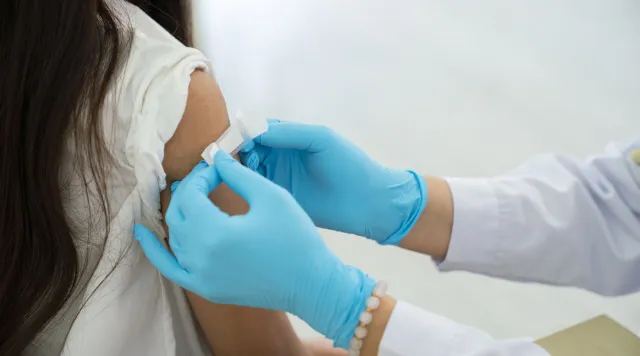Doctor applies bandage to patient's arm following an immunization 